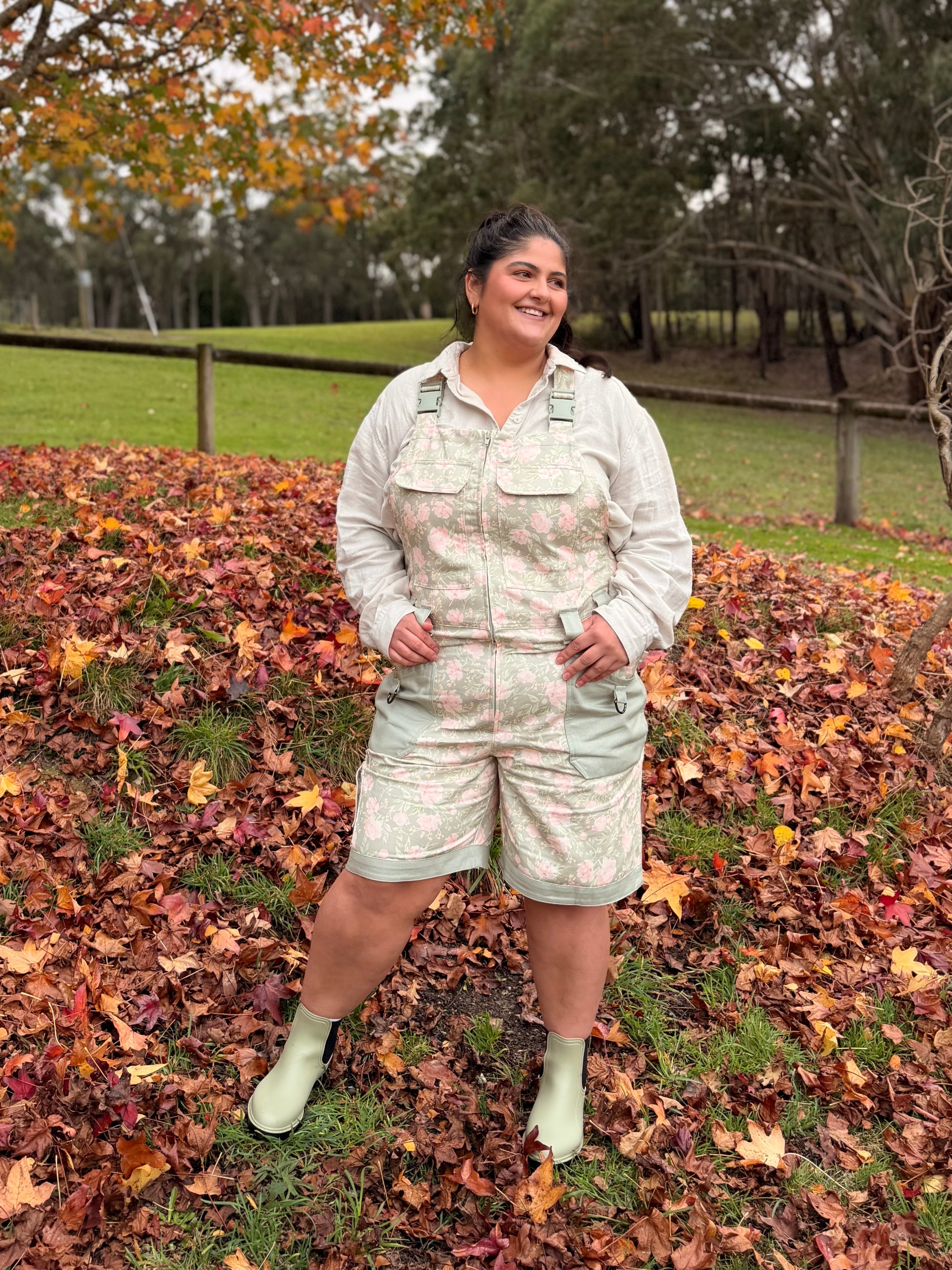 Woman in green floral Peony Meadow Shortalls standing in autumn leaves