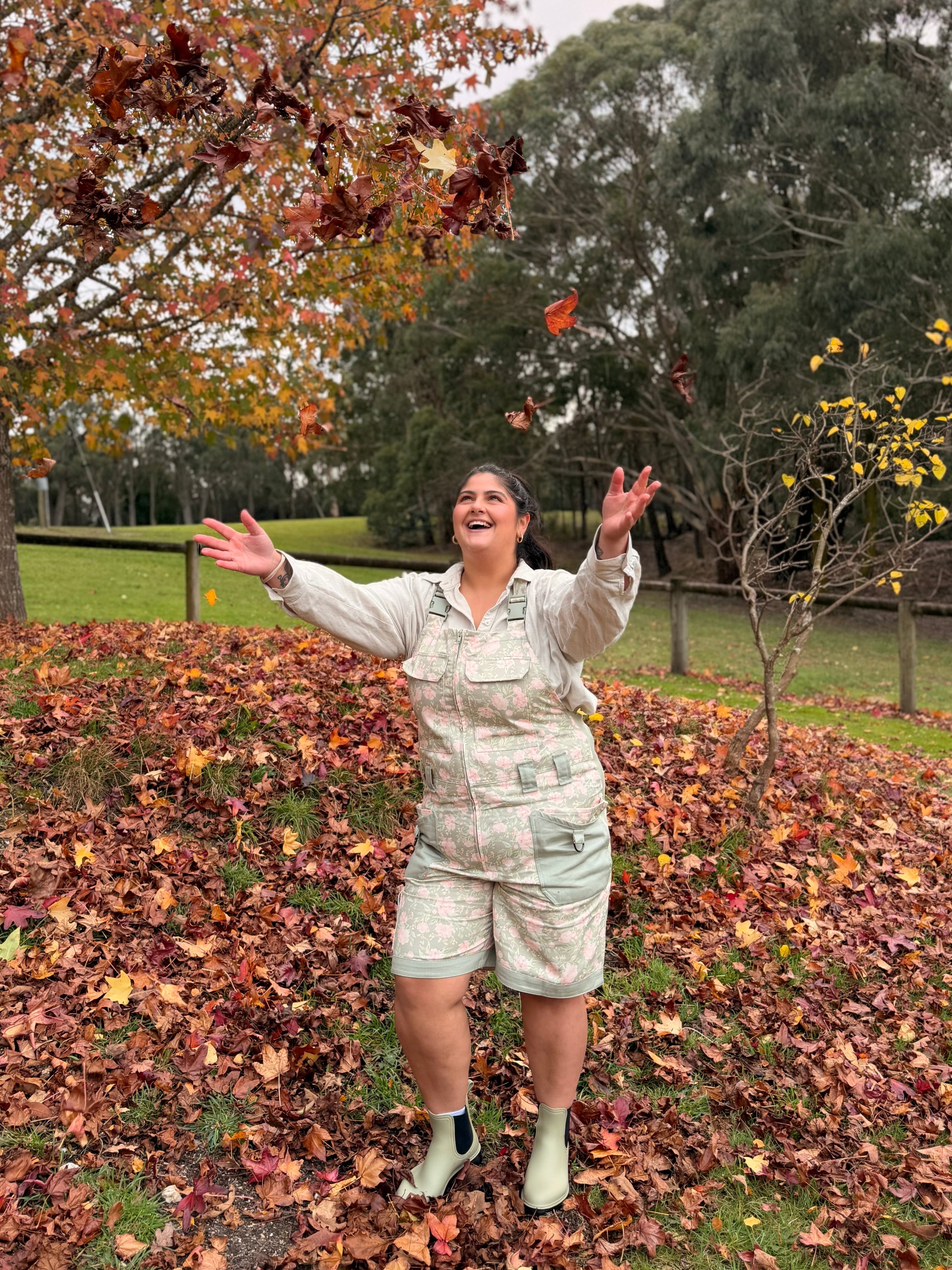 Woman in Peony Meadow Shortalls throwing autumn leaves in the air